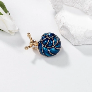 Eleganter Schnecken-Brosche aus Gold mit blauem Emaille und Kristallen auf weißem Grund