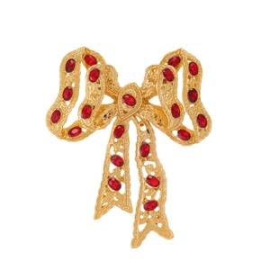 Vintage bow brooch with red crystals and gold filigree on a clean white background