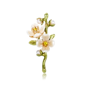 Artistic white floral brooch with yellow crystal and green branch on white background