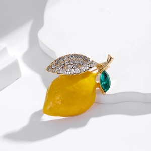 Elegant lemon brooch with yellow enamel and sparkling rhinestones on a white stand