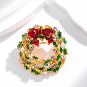 Broche couronne de Noël exquise avec nœud rouge et feuilles vertes sur fond blanc