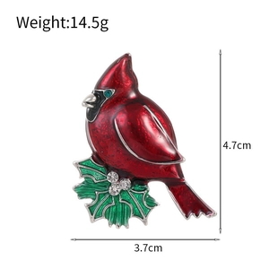 Détail d'une broche oiseau cardinal rouge avec feuilles de houx vertes et cristaux brillants