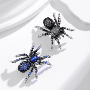 Broche araignée vintage avec strass et œil de chat bleu sur un support blanc
