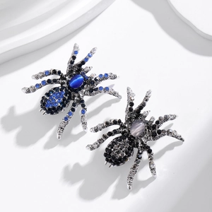 Broches araignée vintage avec strass bleus et gris sur un support blanc élégant