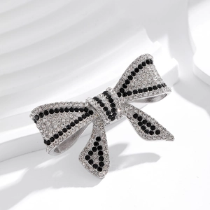 Elegant bow brooch with pearls and rhinestones on a white minimalist display stand