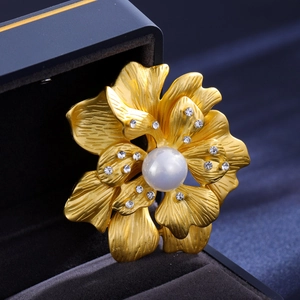 Detail of golden peony brooch with pearls and crystals on blue velvet