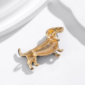 Broche teckel dorée avec fermoir à épingle sur fond géométrique blanc et minimaliste