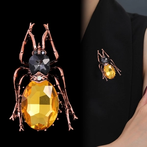 Vintage beetle brooch with yellow crystal and copper finish on a black blazer jacket