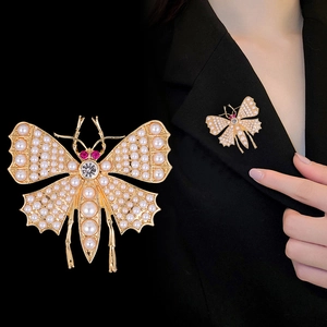 Broche papillon dorée vintage avec perles et cristal sur un revers de costume noir
