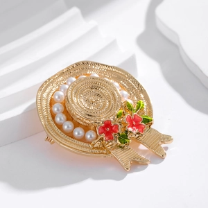 Elegant gold straw hat brooch with pearls and red flowers on a white geometric base