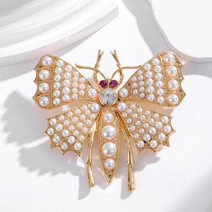 Broche papillon dorée élégante avec perles et cristaux sur un support en marbre blanc