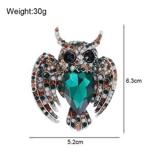 Retro crystal owl brooch featuring a green heart-shaped stone and rhinestone wings