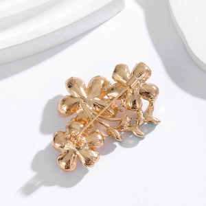 Elegant gold flower brooch with three blooms shown from back side on white stand