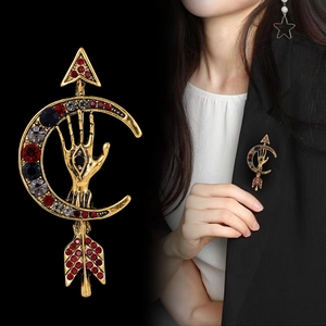 Vintage arrow moon palm brooch with red and blue crystals on a black suit jacket