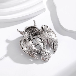 Vintage silver owl brooch with crystal wings and red rhinestone eyes on white stand