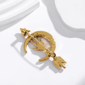 Vintage gold moon and arrow brooch with back safety pin fastener on white background