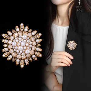 Elegant gold sunflower brooch with pearls and amber crystals on a black suit jacket