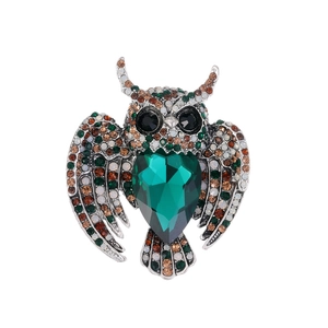 Vintage owl brooch with emerald green crystals and silver metal on a clean white background