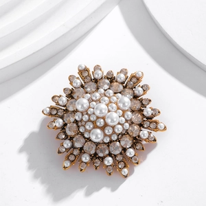 Elegant vintage gold floral brooch with white pearls and champagne crystals on white backdrop