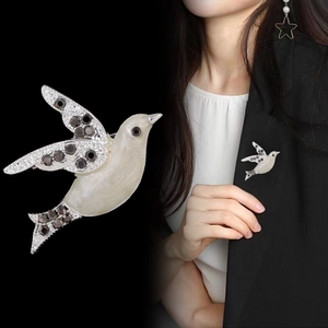 Elegant peace dove brooch with mother-of-pearl finish and black rhinestones on a blazer