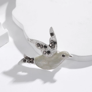 Elegant dove bird brooch in grey enamel and sparkling dark zircons on a white stand