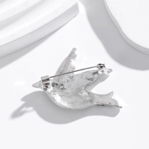 Silver bird brooch back view with metal texture on minimalist stone display
