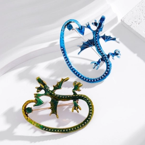 Elegant dragon-shaped brooches in blue and yellow enamel with winged design on white stand