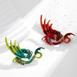 Broches dragons en émail coloré avec cristaux sur fond de pierre blanche minimaliste