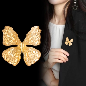 Vintage golden butterfly brooch with embossed texture pinned on a black suit blazer