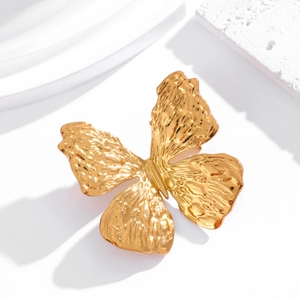 Detailed close-up of golden butterfly brooch with hammered texture on white stone