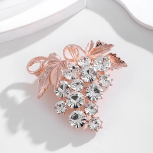 Élégante broche en forme de raisin or rose avec cristaux brillants sur fond blanc épuré