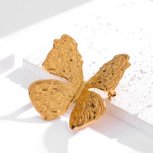 Elegant gold-tone 3D butterfly brooch with hammered texture on a white stone background