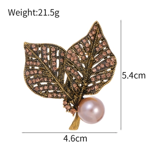 Vintage goldene Blattbrosche mit lila Perle und braunen Strasssteinen auf weißem Grund