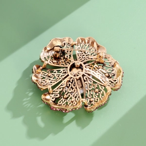 Detailed back view of vintage flower brooch featuring hollow gold metal and pin clasp