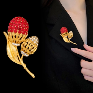 Eleganter Blumen-Anstecker mit roten und weißen Kristallen auf goldener strukturierter Brosche