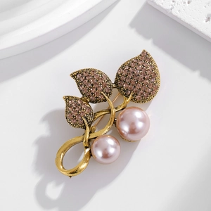 Elegant vintage leaf brooch with pink pearls and crystals on a white stone pedestal