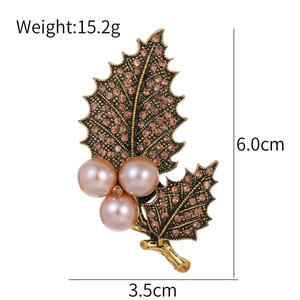 Vintage gold leaf brooch with rhinestones and pink pearls on a white background