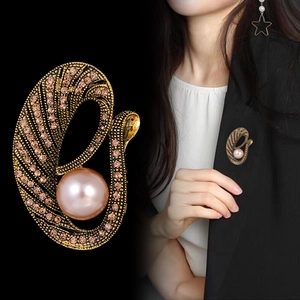 Broche vintage dorado con perlas rosas y cristales en una chaqueta de traje negra
