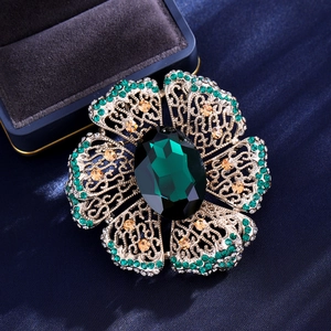 Vintage floral brooch with green oval crystal and gold openwork on blue silk