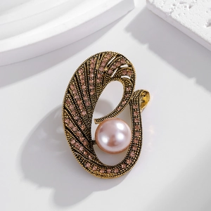 Broche vintage dorado con strass rosa y perla grande sobre pedestal blanco