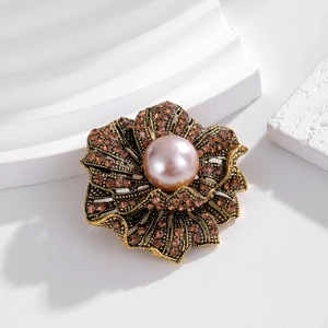 Vintage floral brooch with amber rhinestones and pink pearl on a white pedestal