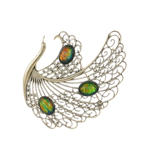 Vintage gold peacock brooch with filigree feather detail and colorful opal inlays