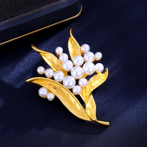 Vintage floral pearl brooch in matte gold finish on an elegant deep blue velvet backdrop