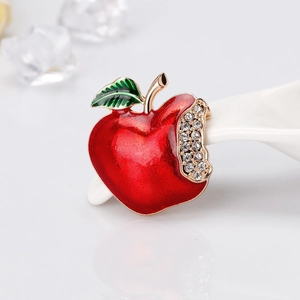 Red enamel apple brooch with green leaf and rhinestone bite detail on golden base
