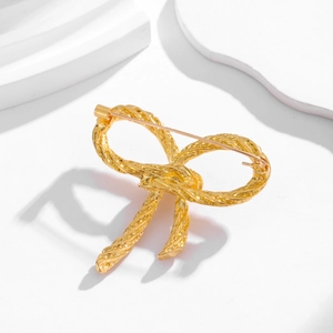 Vintage golden bow brooch with twisted rope texture on a modern geometric display stand