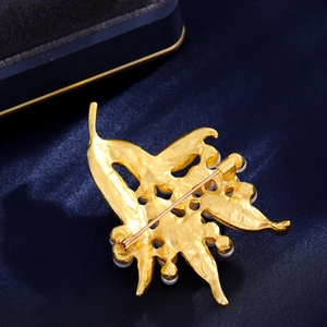 Golden leaf bouquet brooch with white pearls on a navy blue silk background