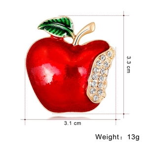 Elegant red apple brooch with rhinestones and gold accents on a white background