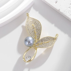 Elegant gold leaf brooch featuring a large grey pearl and sparkling pavé crystal accents