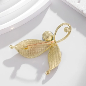 Elegant gold leaf brooch with hammered texture and pearl detail on a white background