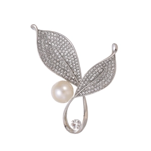 Elegant silver leaf brooch with pearls and sparkling crystals on a white background